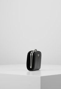 Portefeuille en cuir noir au design élégant, avec quincaillerie argentée et fermeture à clasp. Il présente une forme rectangulaire et une texture lisse.