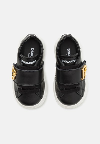 Schwarze Lederschuhe mit weißen Sohlen, ausgestattet mit einem goldenen Schnallenverschluss und schwarzen Schnürsenkeln. Innen mit Branding, rundes zehenförmiges Design.
