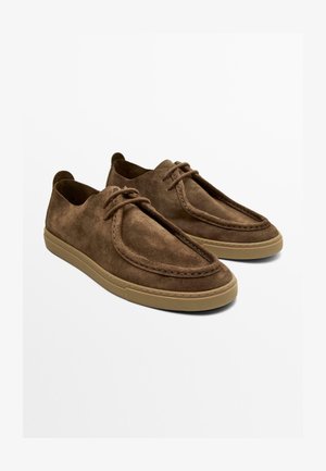 Braune Wildleder-Sneaker mit Schnürung und beigen Gummisohlen, ausgestattet mit Mokassin-ähnlichen Nähten und abgerundetem Zehendesign.