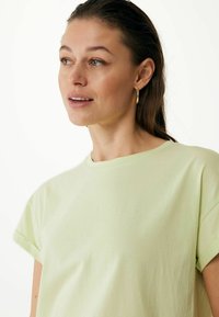 Jasnozielona bawełniana koszulka z krótkim rękawem i okrągłym dekoltem. Miękka w dotyku, o luźnym kroju. Minimalistyczny design bez widocznych wzorów.