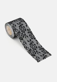 Ruban en dentelle noire avec un motif floral, enroulé sur un bobine en carton. La texture est délicate, mettant en valeur des motifs de roses complexes sur un fond en maille.