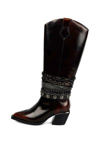 Cizme cowboy maro din piele, cu vârf ascuțit, împodobite cu lanțuri decorative negre și accente argintii la gleznă, cu toc gros.