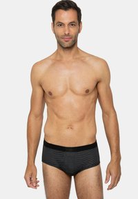 Slip pour homme à rayures noires avec une ceinture noire contrastante, fabriqué dans un matériau lisse et extensible, ajusté près du corps.