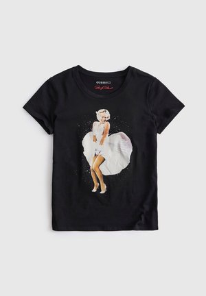 T-shirt noir à manches courtes avec un motif imprimé d'une femme en robe blanche la tenant vers le bas, souriante, au centre devant.