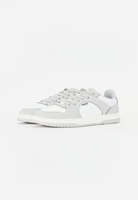 Sneaker grigie chiare con dettagli bianchi, materiale sintetico liscio, punta perforata, lacci rotondi e marchio sul lato. Suola in gomma piatta.
