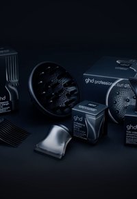 Ensemble d'outils et d'accessoires de coiffure noirs, comprenant des diffuseurs, des peignes et des concentrateurs de coiffage, avec un emballage produit de marque.