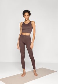 Smeđi rebrasti crop top i tajice visokog struka u uskom dizajnu, s bešavnom teksturom i manžetama do gležnjeva.