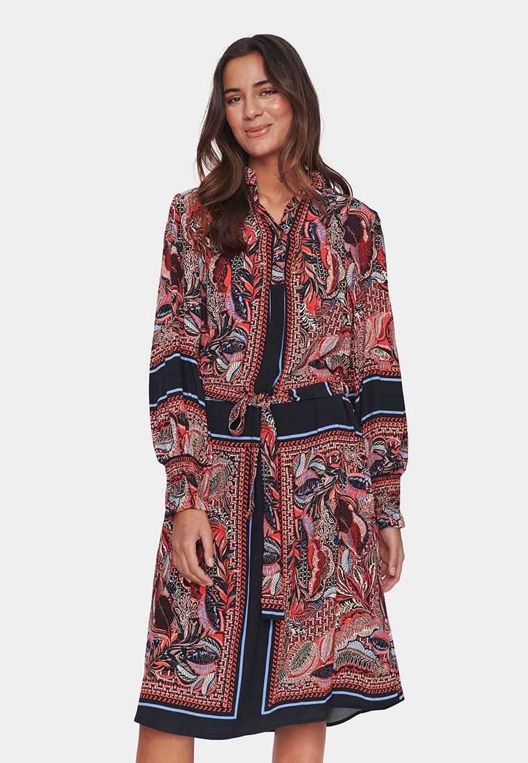 Sukienka z długim rękawem, zapinana na guziki, z nadrukiem kwiatowym i geometrycznym w odcieniach czerwieni, niebieskiego i czarnego, z wcięciem w talii i paskiem do przewiązania.