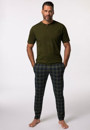 Dunkelgrünes Henley-Shirt mit kurzen Ärmeln, kombiniert mit blauen und grünen karierten Hosen. Weicher Stoff, fester Schnitt und minimalistische Details.