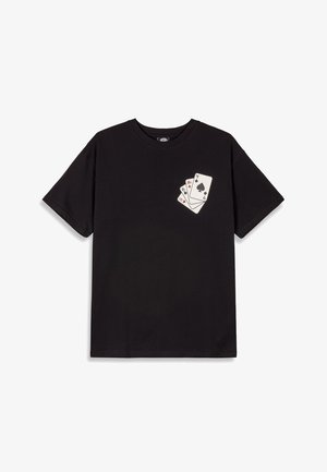 Camiseta de algodón negra con mangas cortas, que presenta un gráfico de tres cartas jugando impreso en la parte izquierda del pecho.