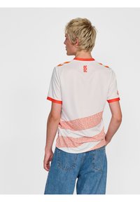 Witte short-sleeve shirt met oranje accenten, voorzien van een gebogen streep patroon en de tekst "QC SC" op de achterkant, gemaakt van lichtgewicht materiaal.