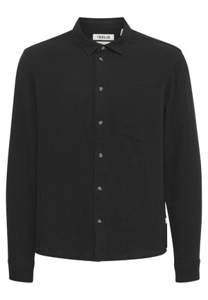 Maglietta nera a maniche lunghe realizzata in tessuto testurizzato. Presenta una chiusura frontale con bottoni, colletto, una tasca sul petto e bottoni marroni.