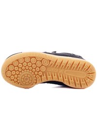 Suela de zapatilla deportiva negra con goma en patrón para agarre; presenta una suela de goma beige y bultitos redondeados y texturizados para mayor tracción.