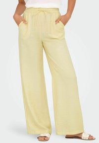 Lichtgele, wijdvallende broek met een elastische tailleband en trekkoord. Bevat zijzakken en een zachte, gestructureerde stof.