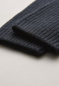 Donkerblauwe ribgebreide stof, dubbelgevouwen, met een zachte textuur en een consistent patroon, geplaatst op een lichte ondergrond.