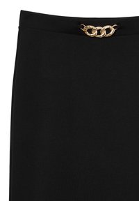 Jupe noire au toucher lisse avec une accentuation en chaîne dorée à la taille, présentant un design plat et sans mécanismes de fermeture visibles.