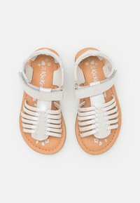 Sandalias de cuero blanco con múltiples correas horizontales, una plantilla texturizada en tono tostado y un acento plateado en la correa del tobillo. Talla 24.