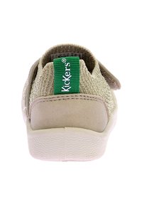 Scarpa in tessuto beige con parte superiore testurizzata, tacco in suede liscio e etichetta verde "Kickers". Presenta una suola in gomma bianca con un delicato motivo a onde.