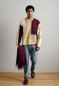 Mitmevärviline kootud kampsun suurte plokkidega kreemikas, burgundia, kollane ja mustrilise äärisega. Sobitatud helesiniste teksade ning burgundia salli juurde.