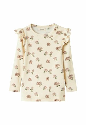 T-shirt à manches longues en crème, avec un motif floral en rose et vert, agrémenté d'un accent à volants sur les épaules.