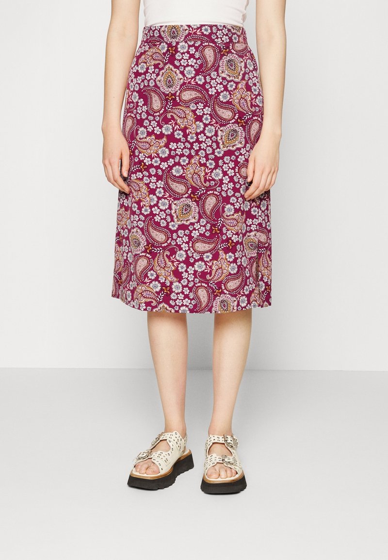 Maroonskirt midi dengan pola bunga dan paisley. Terbuat dari kain ringan. Dipadukan dengan sandal berwarna cerah yang berlubang di latar belakang polos.