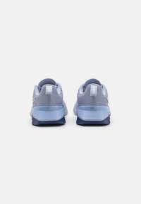 Chaussures de sport bleu clair avec empeigne en mesh, col rembourré et semelle épaisse, dotées d'accents marine et du logo "FUSE" sur le talon.