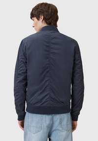 Mørkeblå bomberjakke laget av glatt stoff, med ribbestrikket krage og mansjetter, strømlinjeformet ryggdesign og elastisk midje.