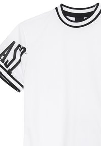 T-shirt bianca concolletto e polsini a righe nere. Presenta una scritta audace in nero sulla manica sinistra. Realizzata in tessuto leggero e texturizzato.
