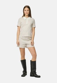 Svītrains divdaļu tērps, kas sastāv no īsām piedurknēm polo krekla ar baltu apkakli un atbilstošām šortiem, kombinēts ar melniem zābakiem līdz ceļgaliem.