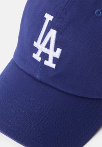 Gorra de béisbol azul marino hecha de tejido texturizado, con un logo bordado en blanco que dice "LA" en la parte frontal y detalles de costura visibles.