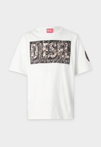 White cotton t-shirt featuring a large, dark graphic print with the word "DIESEL" and abstract leaf patterns, short sleeves, and a crew neckline.