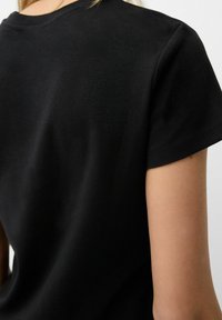 Black cotton t-shirt featuring a crew neckline and short sleeves, with a smooth texture and a relaxed fit. Minimal design with no visible branding.