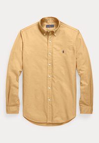 Chemise beige pour homme à manches longues, boutonnée, avec col et petit logo brodé sur la poitrine gauche.