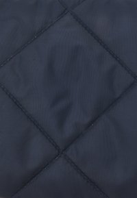 Tecido acolchoado azul marinho com padrão de diamante, apresentando uma textura suave e almofadada e costuras uniformemente alinhadas. Sem hardware ou acentos adicionais.