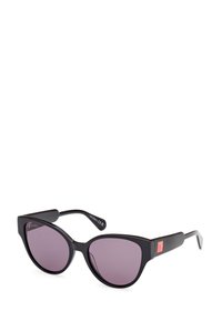 Gafas de sol estilo cat-eye con montura de plástico negro, lentes tintados en púrpura y acentos rectangulares en la patilla. Detalle del logotipo en el costado.