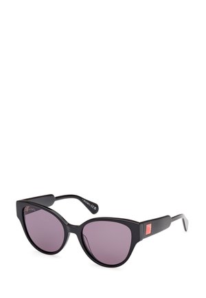 Gafas de sol estilo cat-eye con montura de plástico negro, lentes tintados en púrpura y acentos rectangulares en la patilla. Detalle del logotipo en el costado.
