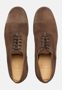 Scarpe in suede marrone con punta rotonda, allacciatura classica e interno in pelle liscia, caratterizzate da un marchio impresso sulle sole.