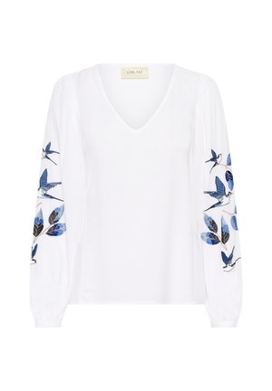 Blouse blanche à manches longues avec décolleté en V, ornée d'oiseaux et de feuilles brodés en bleu et noir sur les deux manches.
