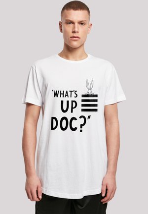 White cotton t-shirt featuring black text "WHAT'S UP DOC?" and a bunny graphic. Loose fit, crew neck, minimalistic design.