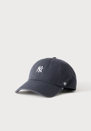Casquette de baseball bleu foncé avec le logo blanc des New York Yankees à l'avant et le logo de la marque '47 sur le côté, posée sur une surface claire.