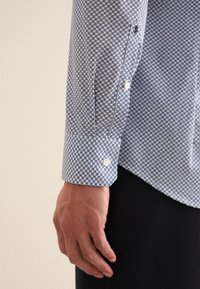 Langarmsgemerk in blauw en wit met een hexagonaal patroon, met een knoopsluiting aan de manchetten en een getailleerde pasvorm. Zachte stoftextuur.