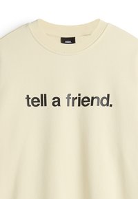 Sudadera color crema con el texto "dile a un amigo." en negrita y negro. Cuello redondo, textura suave y corte casual.
