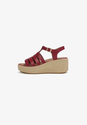Red leather wedge sandal with multiple straps, ankle buckle, and woven platform sole in beige.