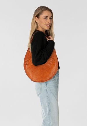 Borsa a spalla rotonda in pelle beige con una consistenza liscia e una tracolla marrone in contrasto. Presenta un design semplice e curvo con hardware minimal.