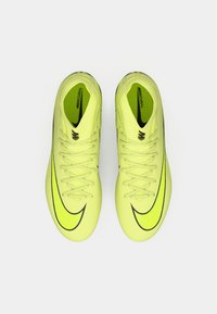 Jasnożółte korki piłkarskie z teksturowaną cholewką, czarnymi akcentami i wyraźnym logo Nike. Posiadają tradycyjny system sznurowania.
