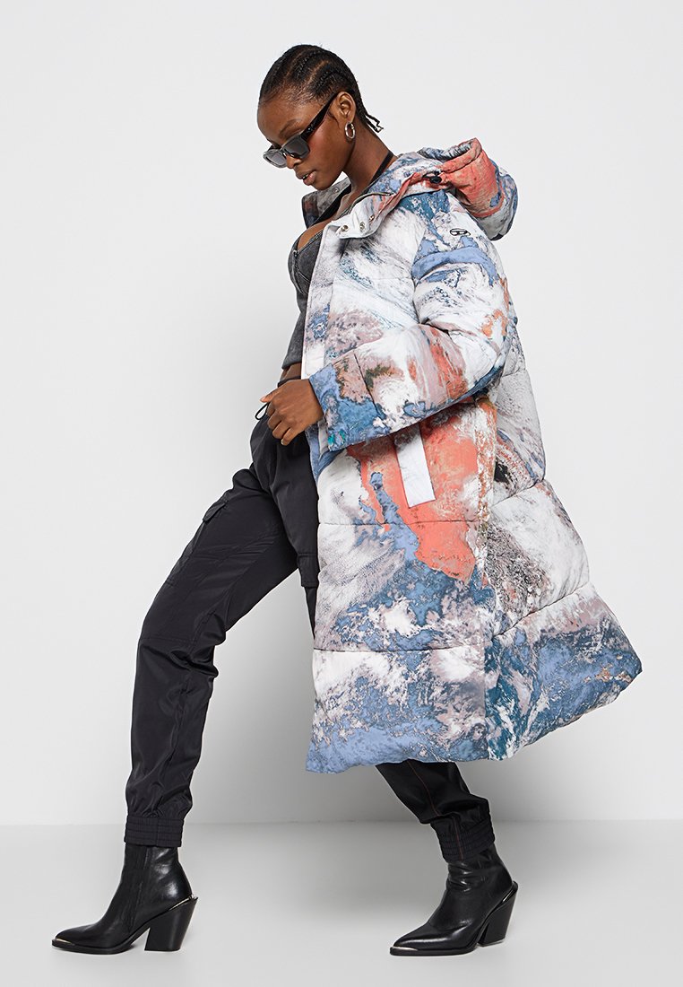 Manteau rembourré arborant un imprimé abstrait multicolore en bleu, corail et blanc, avec une capuche, de grandes poches et une coupe mi-longue.