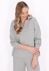 Set di abbigliamento da casa grigio, strutturato, con un motivo geometrico; presenta una maglia oversized con colletto e pantaloni con vita elasticizzata.