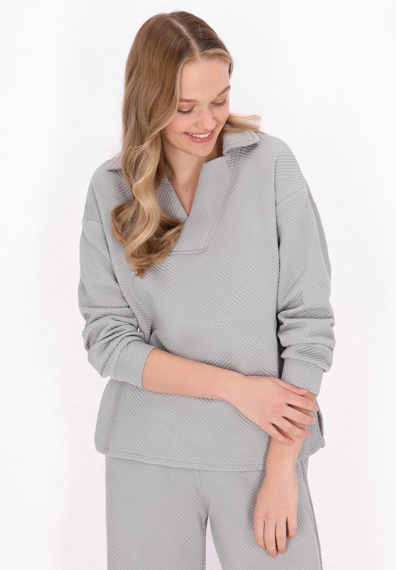 Set di abbigliamento da casa grigio, strutturato, con un motivo geometrico; presenta una maglia oversized con colletto e pantaloni con vita elasticizzata.