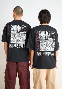 Black cotton t-shirts with large graphic prints on the back. Features a mix of illustrations, text, and contrasting colors. Relaxed fit.
