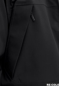 Čierna softshellová bunda s diagonálnou kapsou a čiernym zipsom, hladká textúra a minimalistický dizajn. Navrhnutá pre funkčnosť.